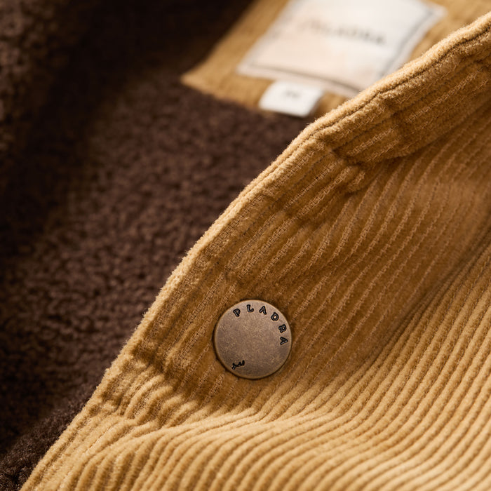Close-up of Pladra Men's Ironwood Sherpa Jacket in Acorn Tan cotton corduroy with metal button and brown fleece lining.