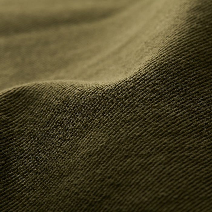 Close-up of hunter green, ribbed fabric with gentle folds, featured on Pladra's Men's Sequoia Chore Coat.