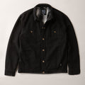 The Men's Sequoia Jacket- Shadow Black, made from black cotton twill with metal buttons, chest flap pockets, and side pockets, is laid flat on a light-colored surface.