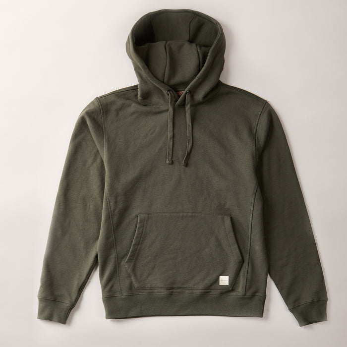 The Men's Sierra Hoodie in Pine Green is a premium heavyweight French terry cotton hoodie with a front pocket, drawstring hood, ribbed cuffs and hem, and a small white tag on the pocket corner. Shown flat on a light background.