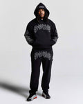 Person wearing a black hoodie and pants with white text on a light gray background