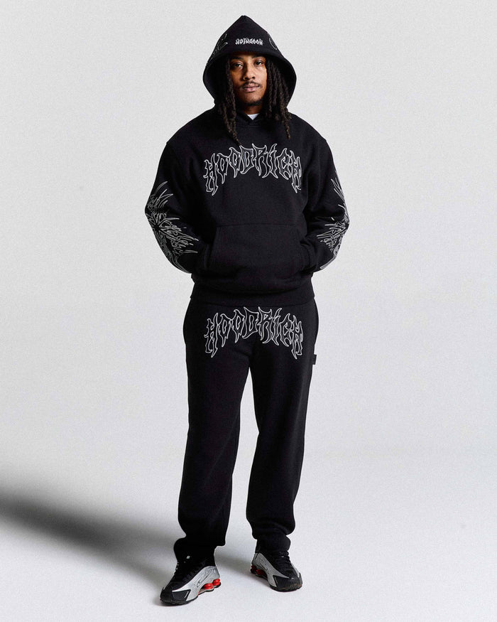 Person wearing a black hoodie and pants with white text on a light gray background