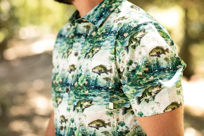 A man wears the Pladra Men's S/S Printed Outdoor Aloha Shirt - Bass in sunlight.