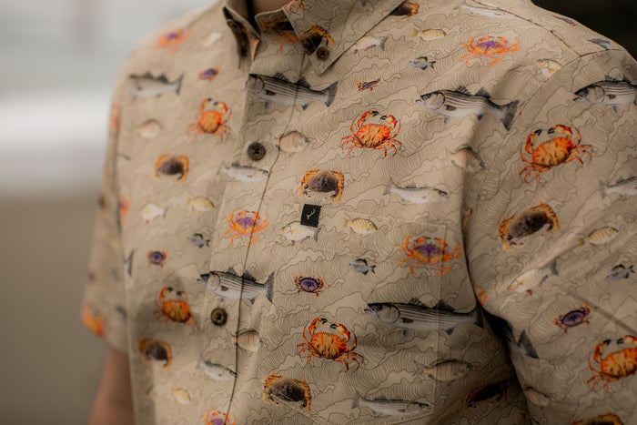 The Pladra Men's S/S Printed Outdoor Aloha Shirt in beige features a colorful crab, fish, and shell pattern.