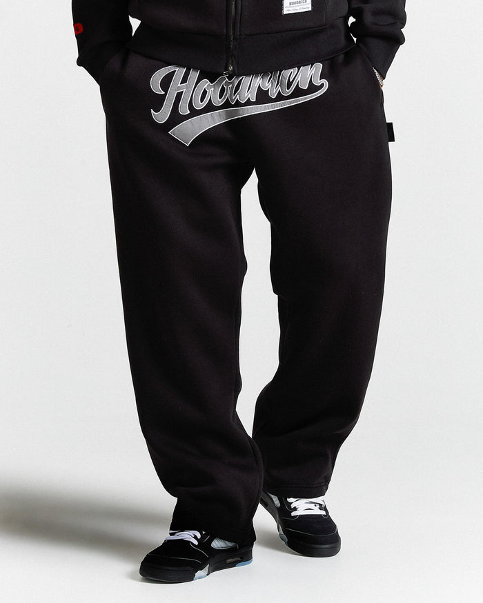 Black pants with 'Hoodman' logo worn by a person on a white background
