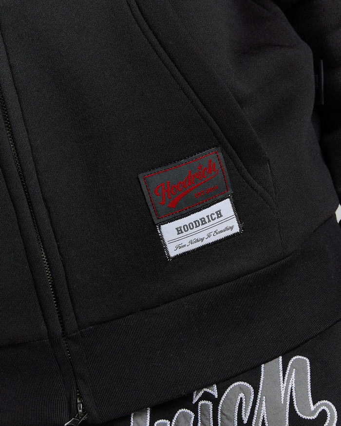Close-up of a black jacket with a brand label on the chest.