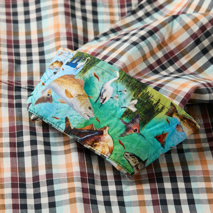 A close-up of the Men's Tailwinds Shirt in Pebble Brown shows its cuff turned up, revealing a colorful inner lining with various fish swimming in a blue-green underwater scene.