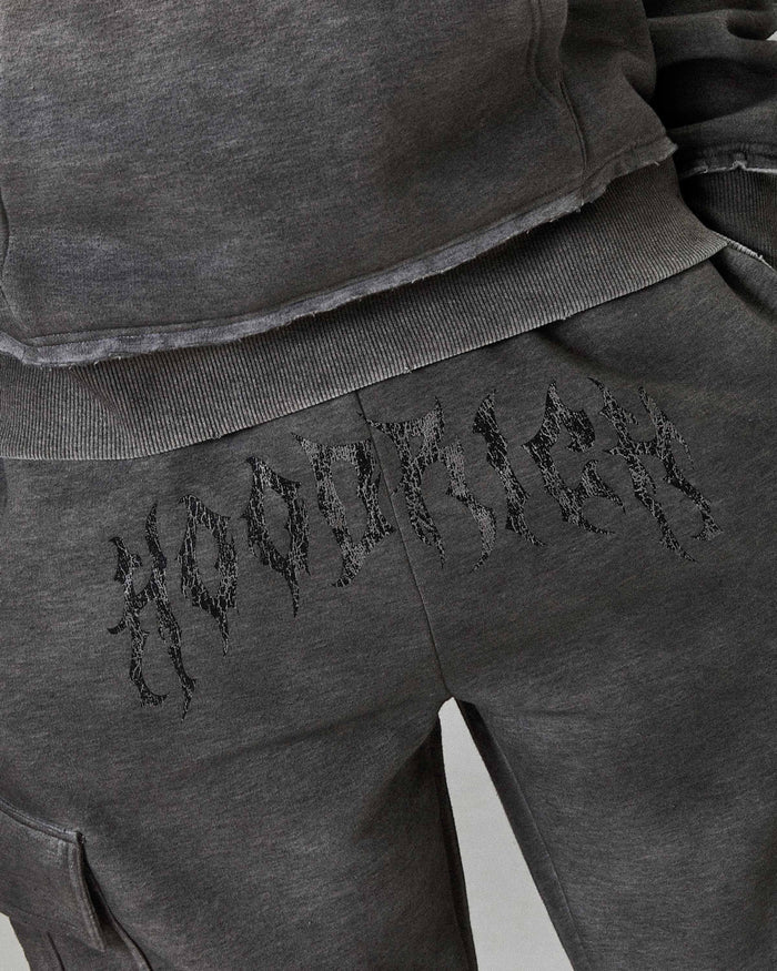 Gray sweatshirt and pants with embroidered text on a plain background