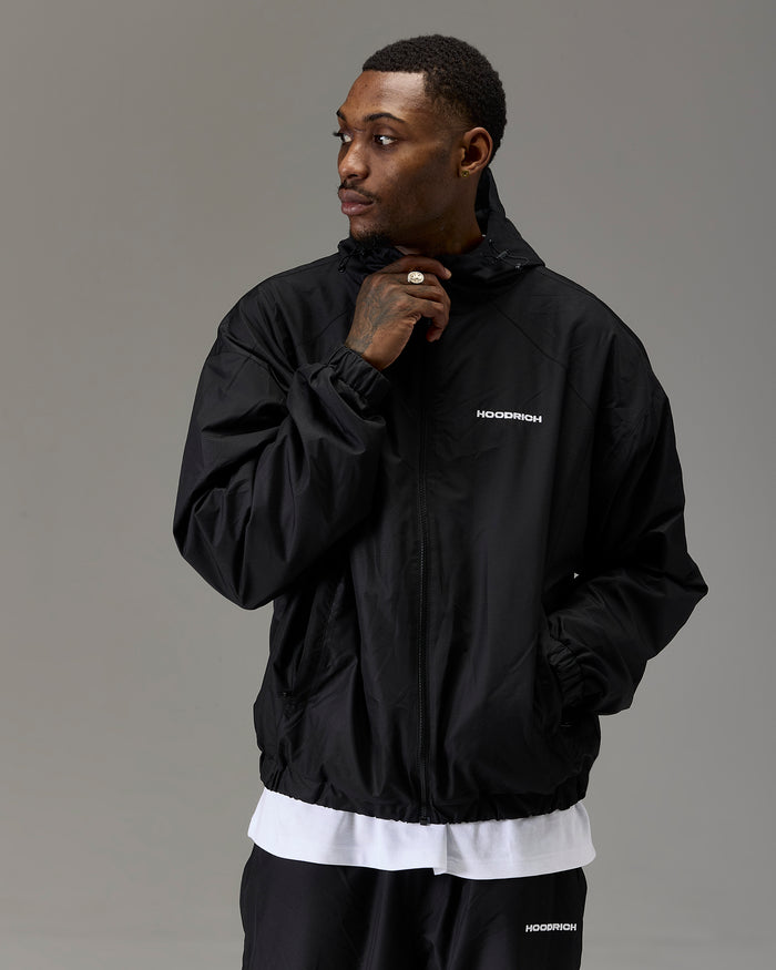 Displays a model wearing the Black 'Hoodrich' branded Men's The Winner's Circle Ripstop Woven Full Tracksuit