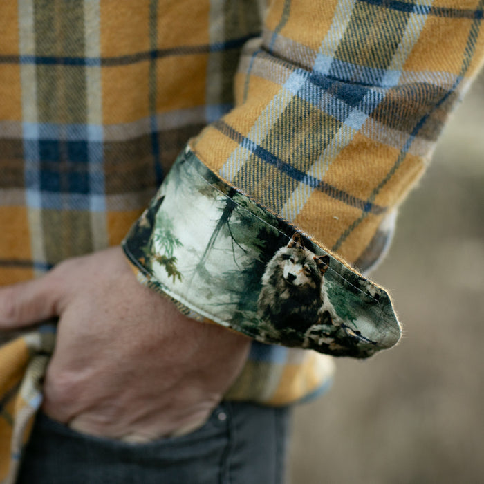 A man wears the Pladra Men's Workhorse Elite Flannel Shirt in Easton Gold, hand in pocket.