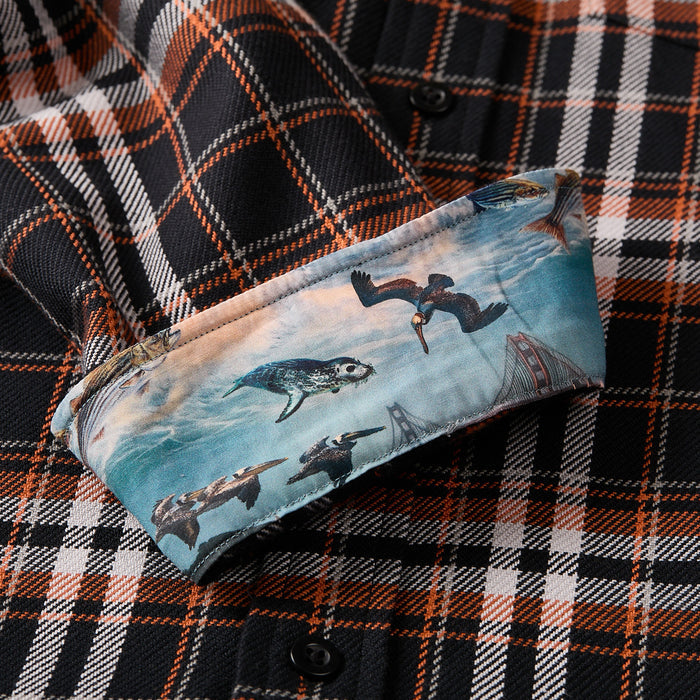 The Men's Workhorse Elite Flannel Shirt - Posey Black is a black, orange, and white Portuguese flannel shirt with turned-up cuffs showcasing a vibrant print of birds, a sea turtle, waves, and bridge structures.