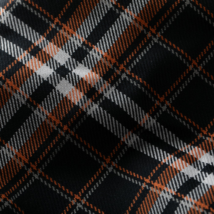 Close-up of the Men's Workhorse Elite Flannel Shirt- Posey Black, featuring a plaid pattern in black, white, gray, and orange. The intersecting lines form a classic tartan design on slightly wrinkled heavyweight cotton fabric.