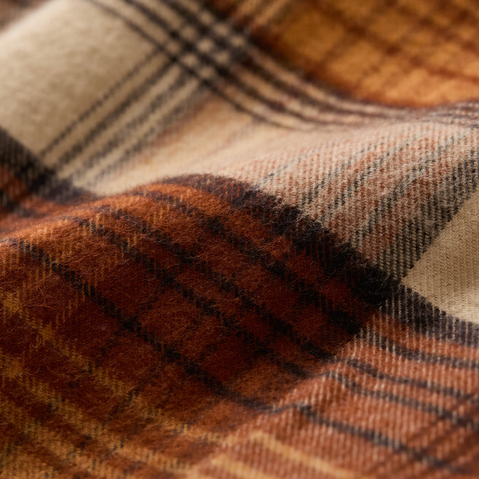 Close-up of the Men's Workhorse Flannel Shirt in Sedona Orange, showing its soft, textured Portuguese flannel with a brown, orange, black, and cream plaid pattern. The warm, heavyweight cotton material features gentle folds and visible fibers.
