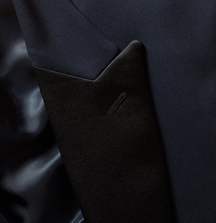 Close-up of midnight blue tuxedo jacket with black satin peak lapel and welt pocket