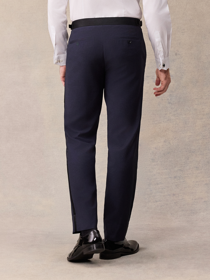 Back view of man in midnight blue tuxedo pants with black satin waistband tab