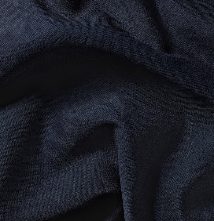 Close-up of midnight blue tuxedo fabric with soft folds and woven texture