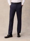 Man in midnight blue tuxedo pants with black satin waistband tab, hands in pockets, front view