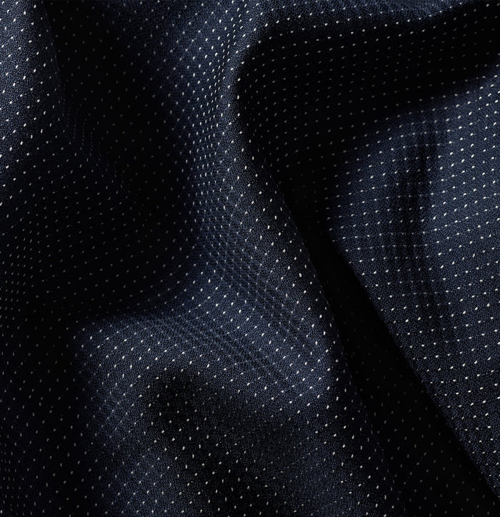 Close-up of midnight pin dot tuxedo fabric with folds, showing subtle dot pattern
