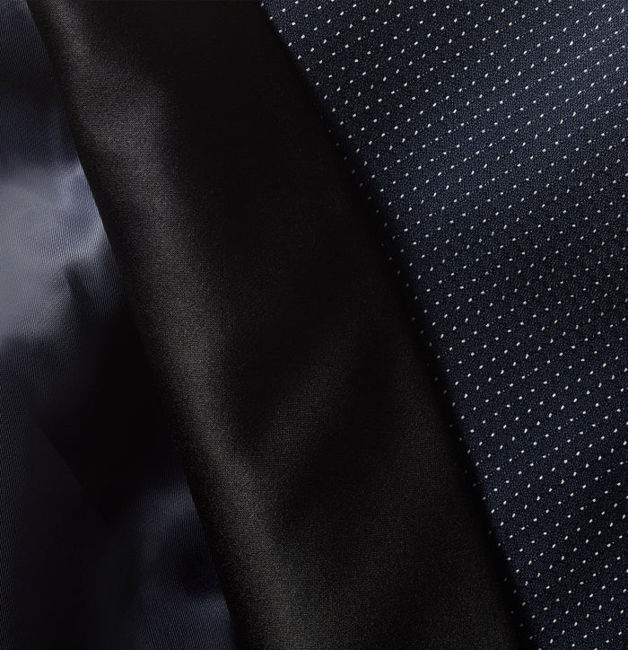 Close-up of midnight pin dot tuxedo fabric next to black satin lapel edge