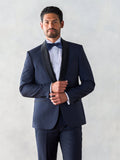 Man in midnight shawl-lapel tuxedo, black satin lapel and bow tie, holding lapel, front view