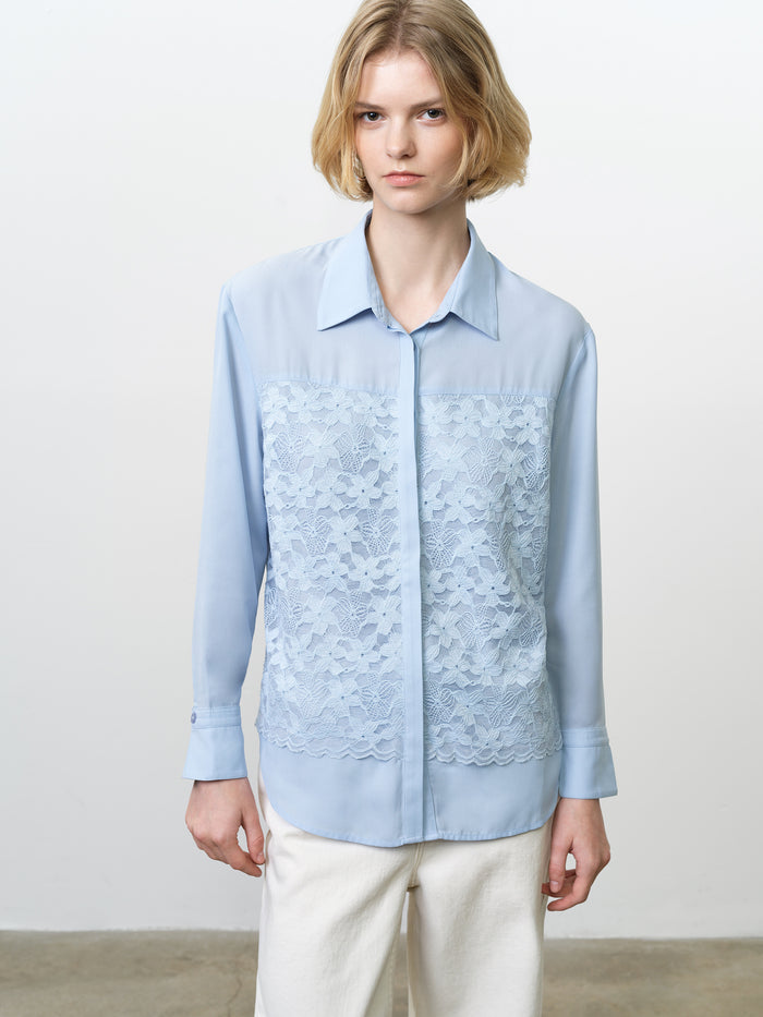 Woman wearing a long sleeve, light blue shirt with a lace front overlay
