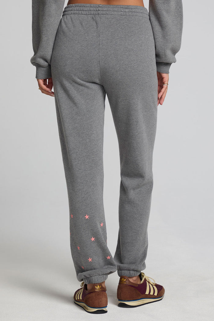 Back view of a woman wearing the Chaser Mini Star Glaze Pants and matching grey sweatshirt on a neutral background