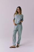 Full body view of woman wearing Chaser's Mission Joggers in garden green sage with the matching Amelia pullover on a plain background