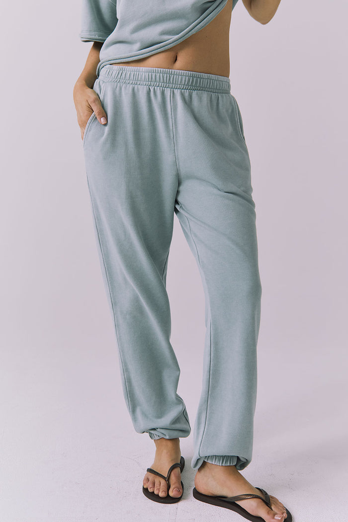 Front view of woman wearing Chaser's Mission Joggers in garden green sage on a plain background