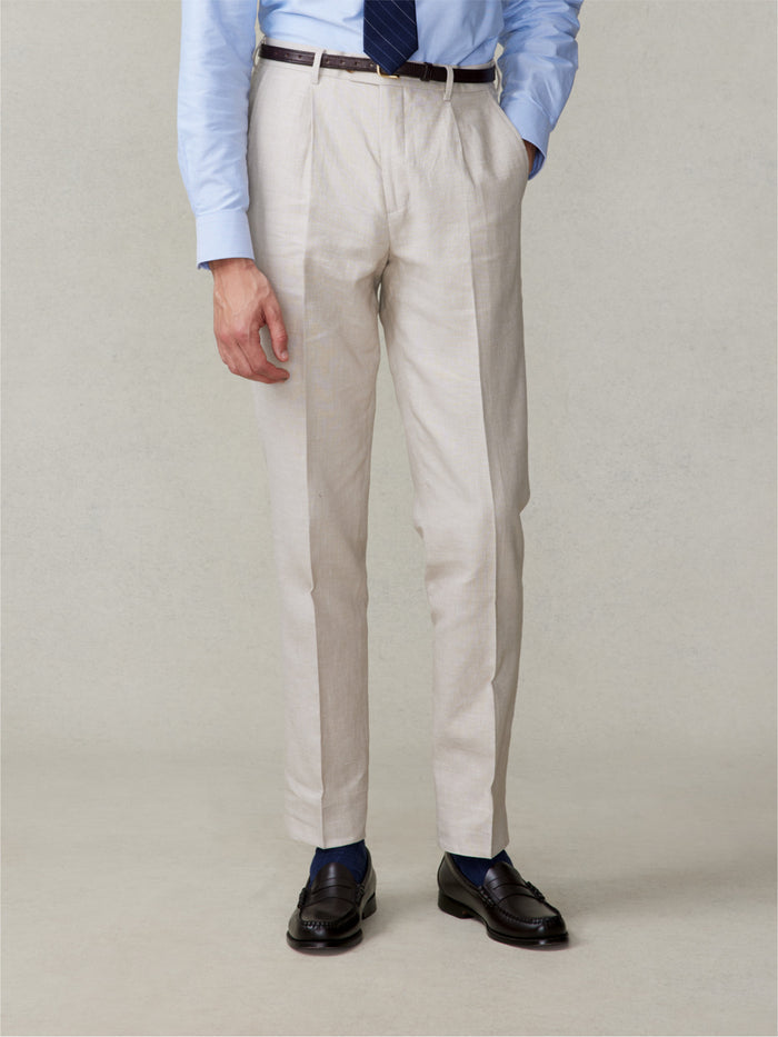 Close-up of man in mojave tan linen pleated pants, light blue shirt, navy tie, front view