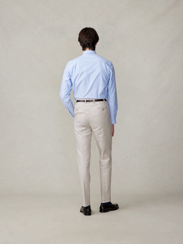 Back view of man in mojave tan linen pants, light blue shirt, belt, full length