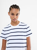A woman wearing a white short sleeved top with black stripes, a crew neck and a relaxed fit.