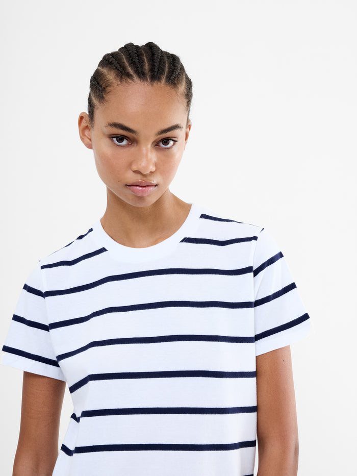 A woman wearing a white short sleeved top with black stripes, a crew neck and a relaxed fit.
