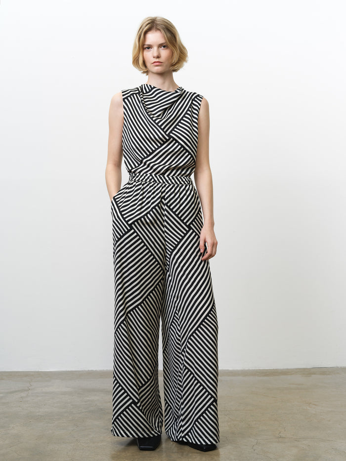 Woman wearing high waisted wide leg trousers, in a black and white asymmetric striped print