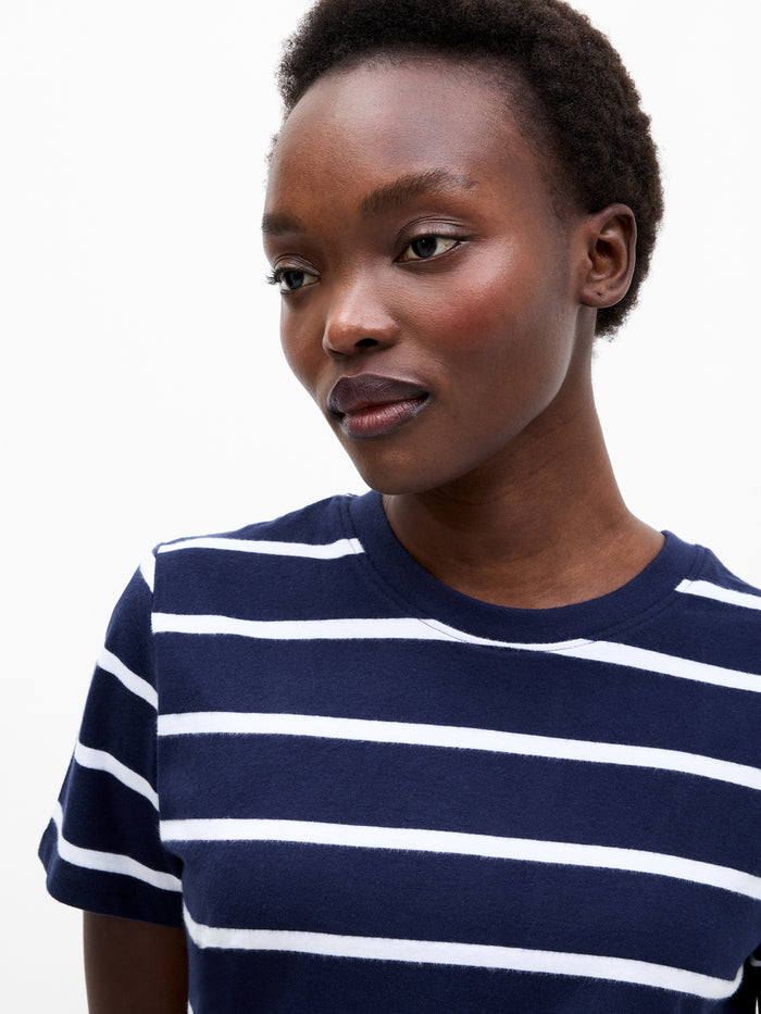 A woman wearing a dark blue short sleeved top with white stripes, a crew neck and a relaxed fit.