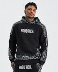 A male model wearing a black hoodie with 'HOODRICH' text and motif print design.