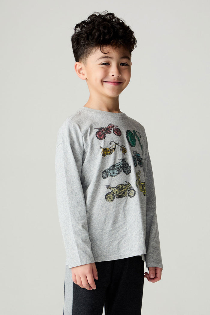 Side angle view of a boy wearing the Chaser Moto Boys Tee and black pants on a neutral background
