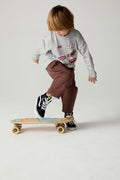 Boy riding a skateboard while wearing the Chaser Moto Patches Boys Tee on a neutral background