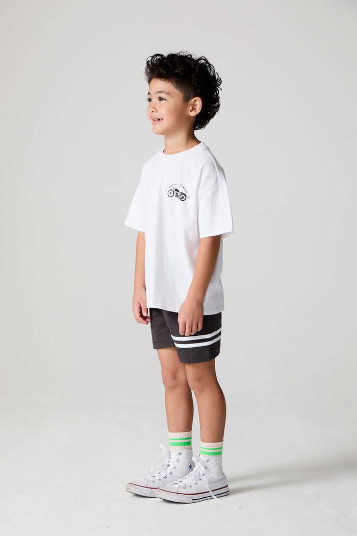 Full body side view of a boy wearing the Chaser  Motor Racing Tee on a neutral background