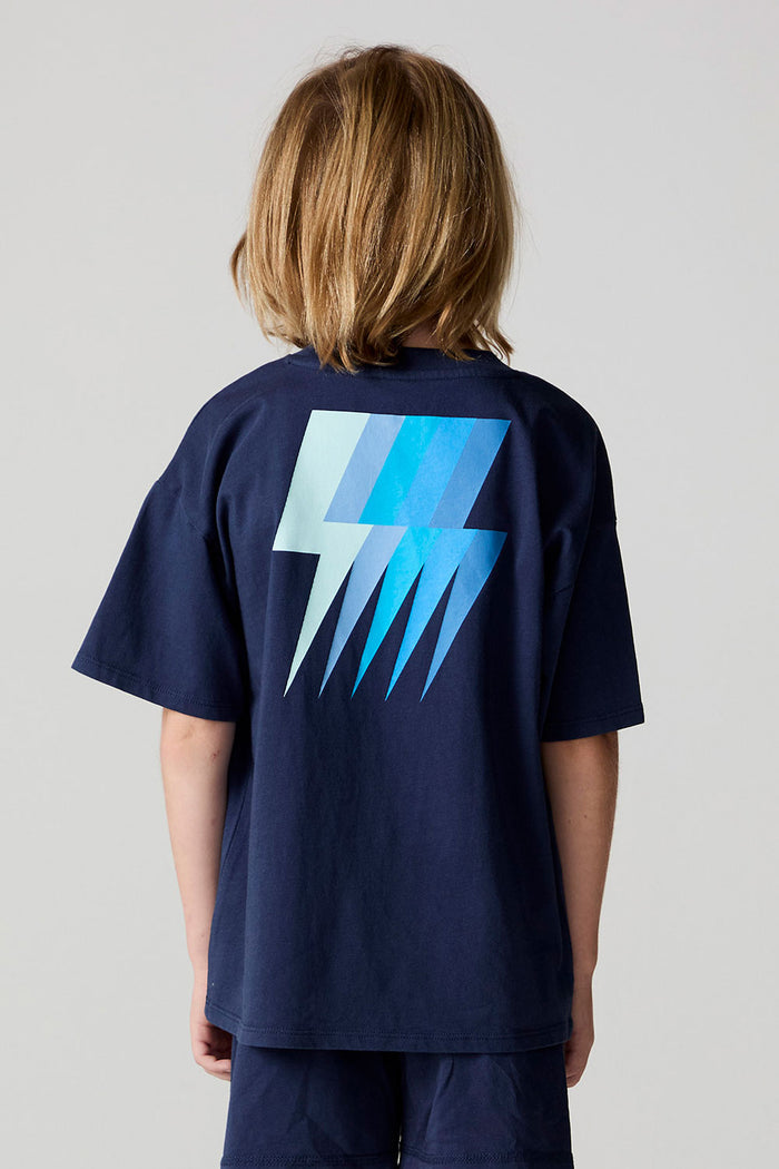 Back view of a boy wearing the Chaser Multi Bolt Tee on a neutral background
