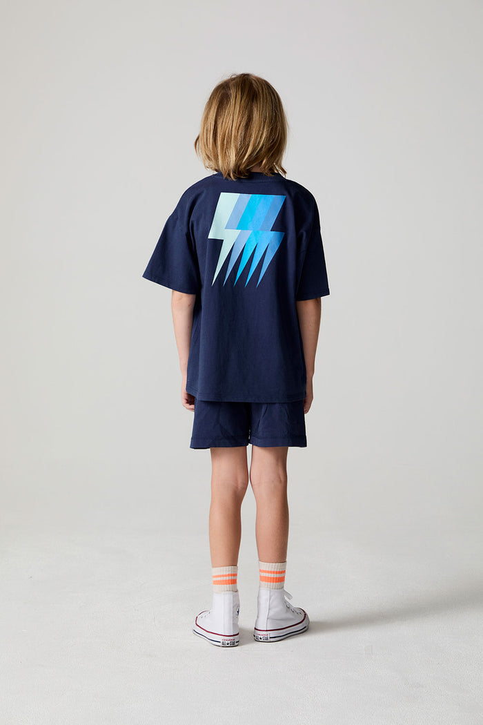 Full body back view of a boy wearing the Chaser Multi Bolt Tee on a neutral background