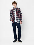 A man wearing a maroon and blue checked shirt with long sleeves, a button down fastening and a shirt collar.