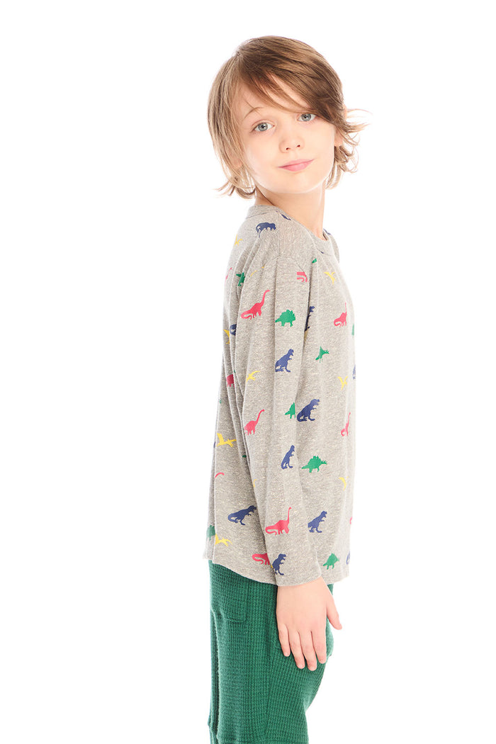 Side view of boy wearing Chaser’s Multi Dinos grey long sleeve top with colorful dinosaur patterns against a white background