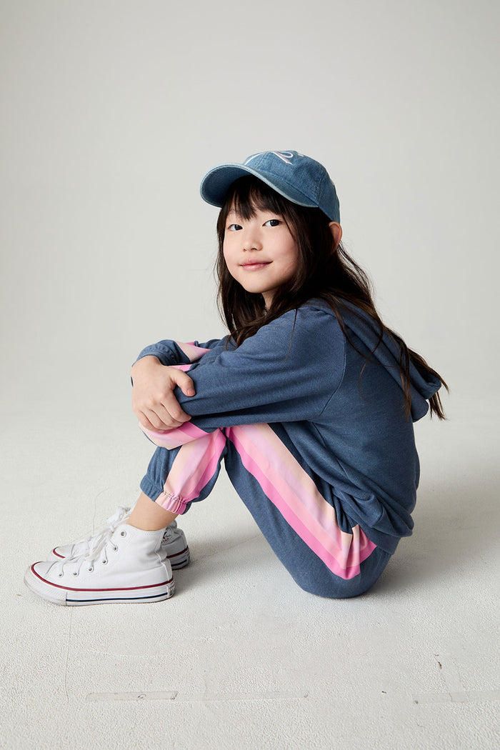 Seated girl wearing the Chaser Multi Stripes Girls Jogger on a neutral background with pants