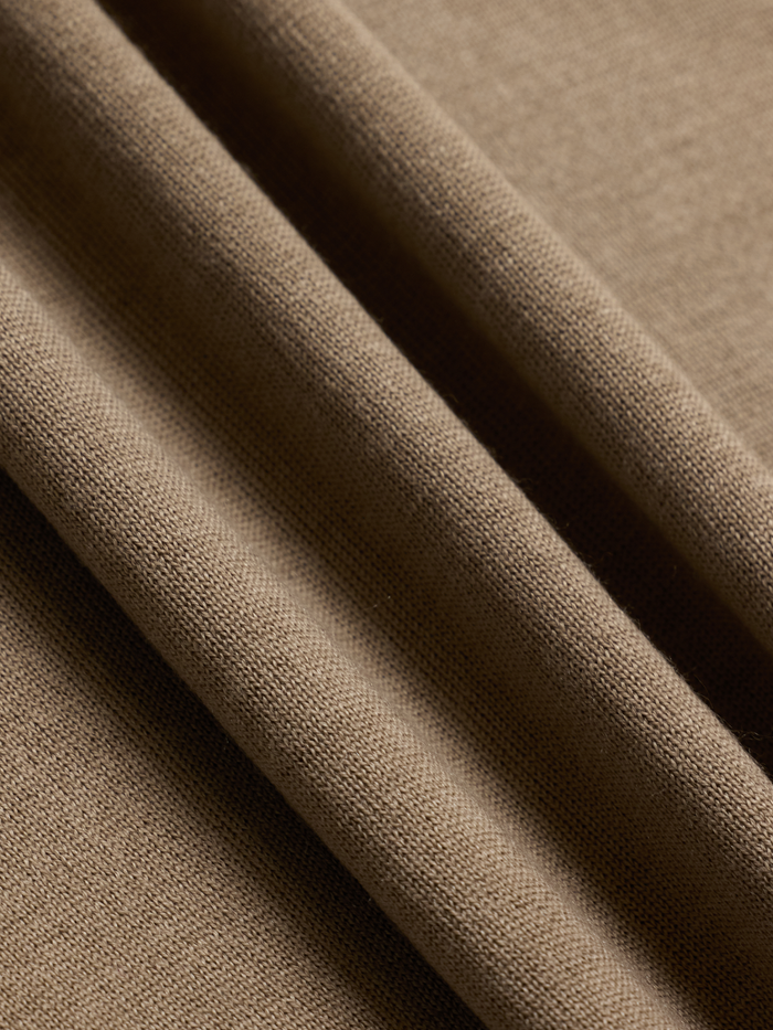 Close-up of mushroom brown sweater knit fabric with folds, showing ribbed texture