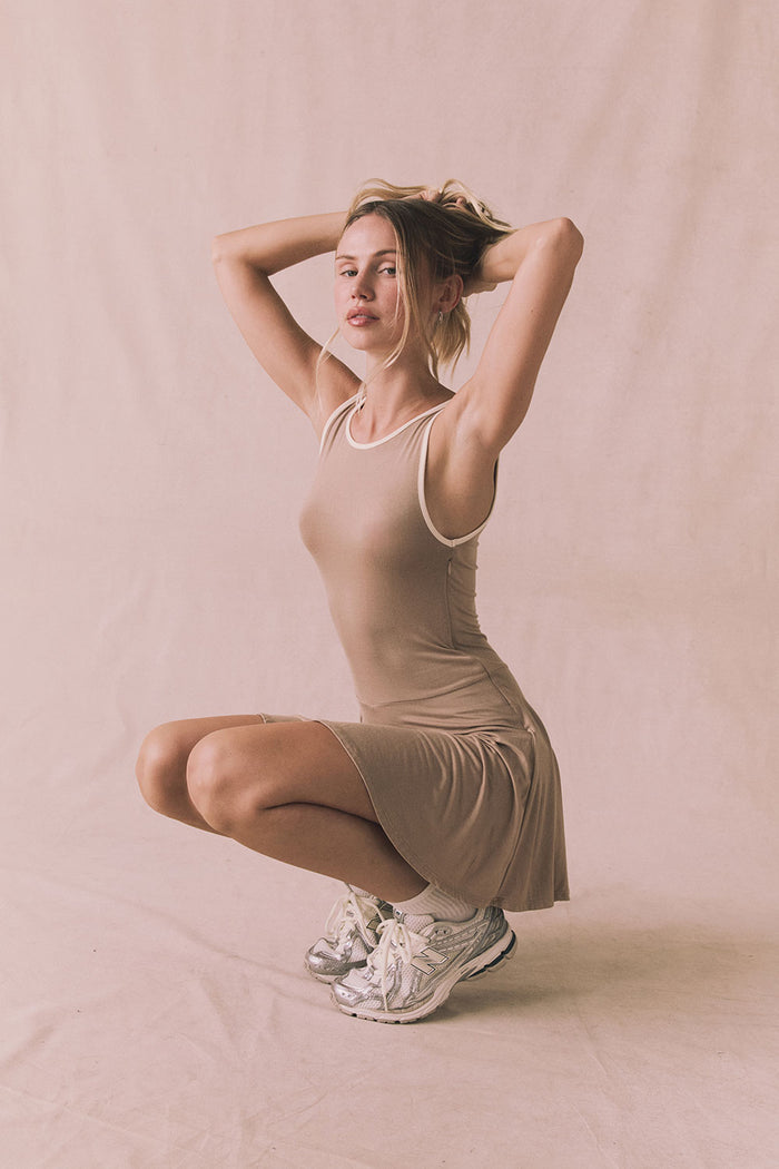 Editorial full body view of Chaser Brand Myrina Iced Coffee Mini Dress with model lifting her arms and showing soft stretch fit