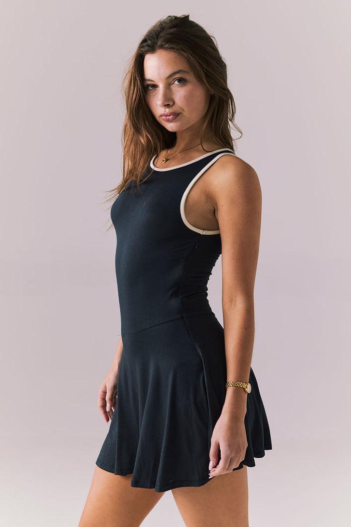 Side angle view of Chaser Brand Myrina Licorice Black Mini Dress highlighting the soft drape and easy movement of the flared mini hem