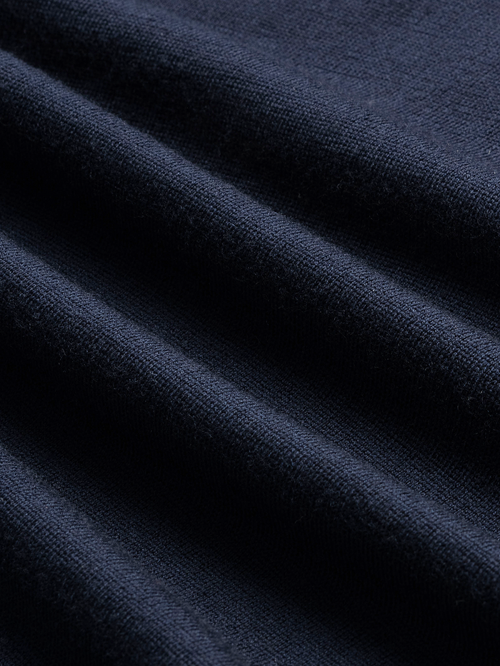 Close-up of navy sweater knit fabric with folds, showing textured weave