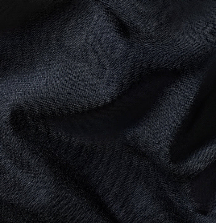Close-up of navy blue suit fabric with folds, showing woven texture