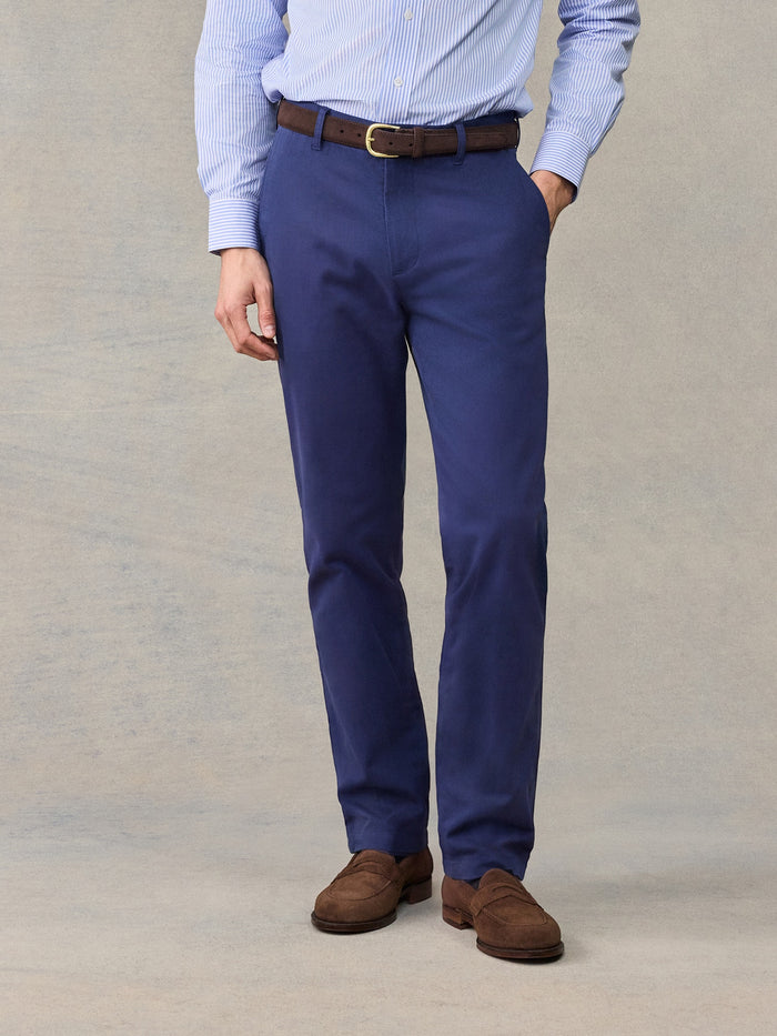 Close-up of man in navy chino pants with brown belt, light blue striped shirt, front view