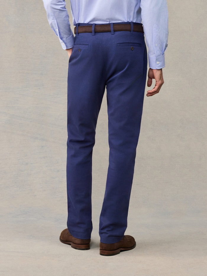 Back view close-up of man in navy chino pants with brown belt, light blue striped shirt